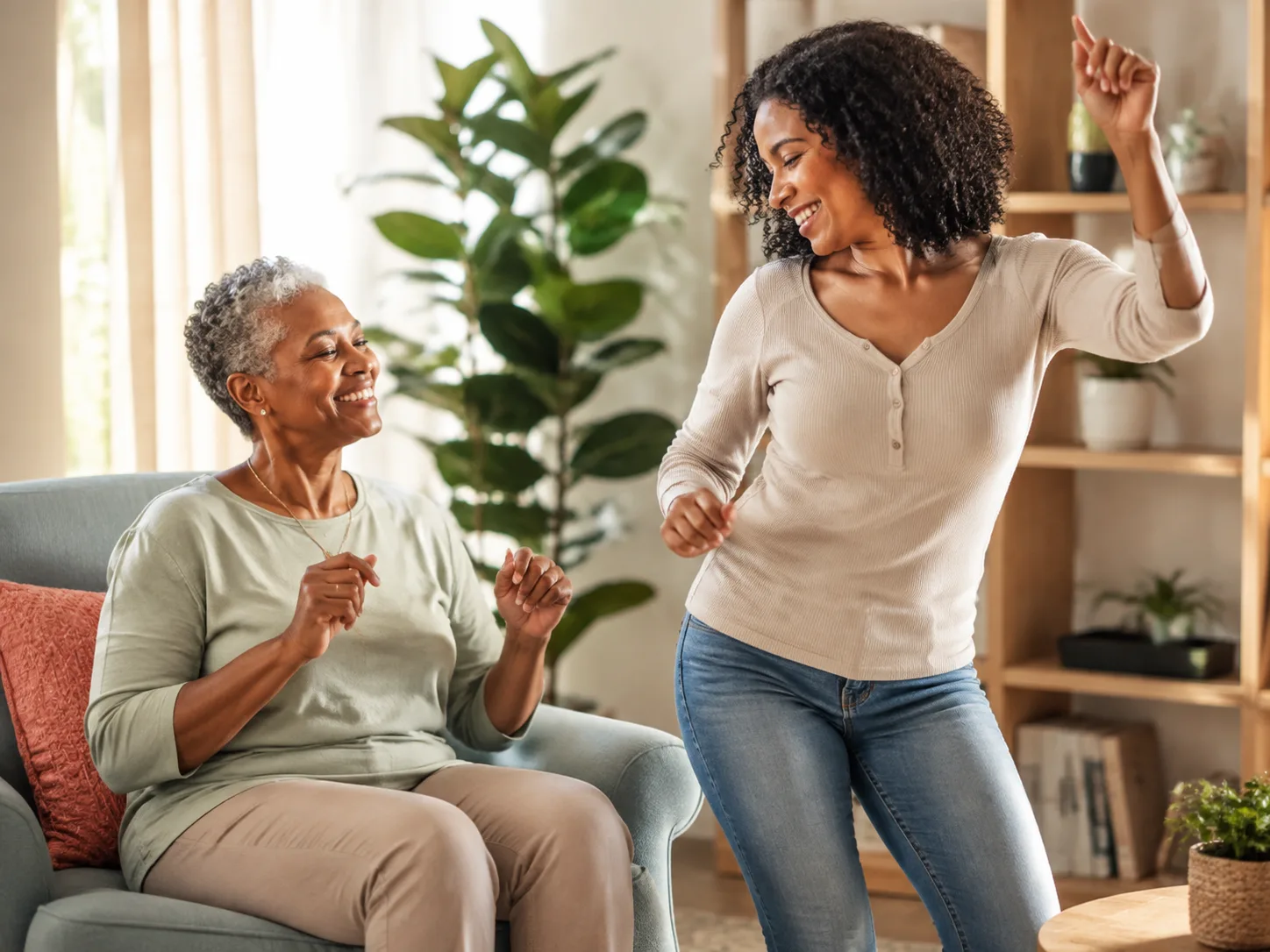 An older woman and her caregiver dancing and laughing in the living room